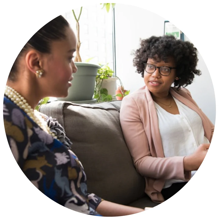 Two women sitting on a couch in conversation.