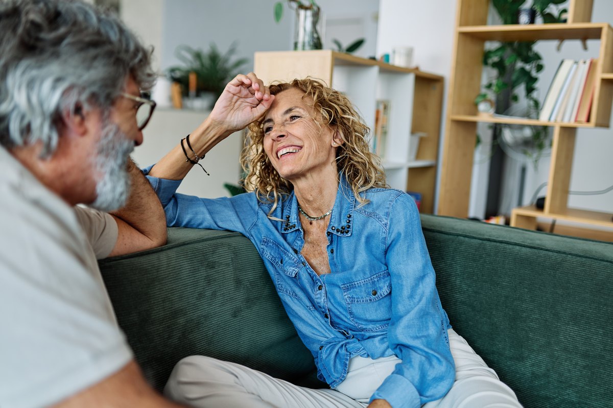 An older couple sitting together on a couch at home.
