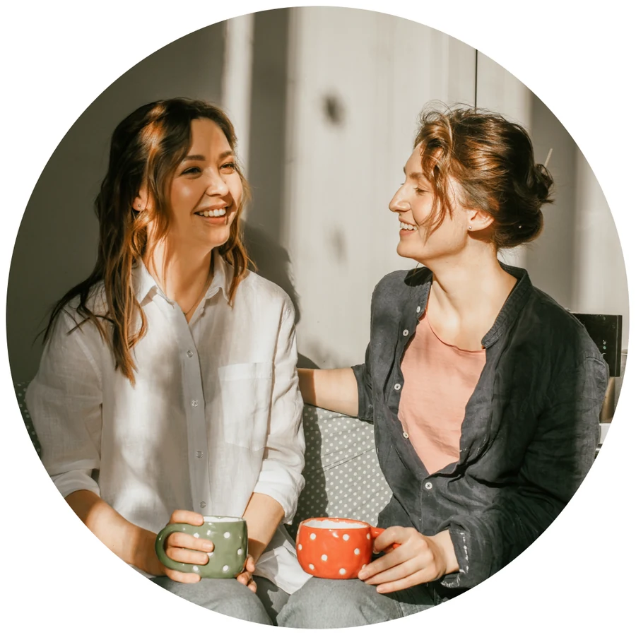 Two women holding mugs and talking.